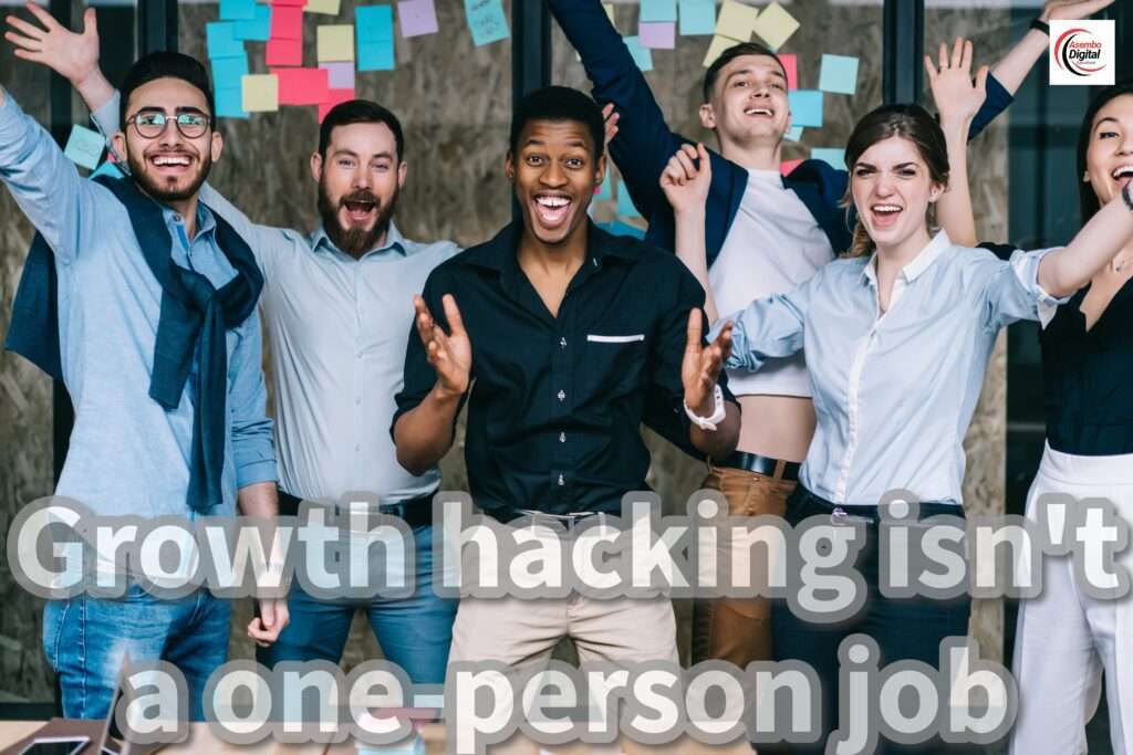 "A diverse group of six enthusiastic team members celebrating together in an office, standing in front of a wall filled with colorful sticky notes. The text 'Growth hacking isn't a one-person job' is prominently displayed over the image. The logo for Asembo Digital Solutions is visible in the top-right corner."